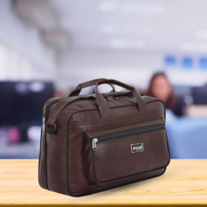 Professional brown faux-leather office messenger bag with top handles, adjustable shoulder strap, and multiple zippered compartments, displayed on a wooden surface with a blurred office background.