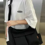 Large black canvas messenger shoulder bag with multiple pockets and adjustable strap
