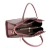 Elegant pink structured handbag for women carried by a model, featuring dual top handles, detachable shoulder strap, textured finish, and gold-tone hardware.