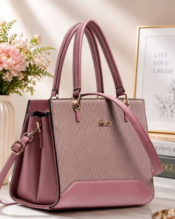 Premium pink structured handbag for women with dual handles, detachable shoulder strap, textured finish, and spacious compartments for daily use.